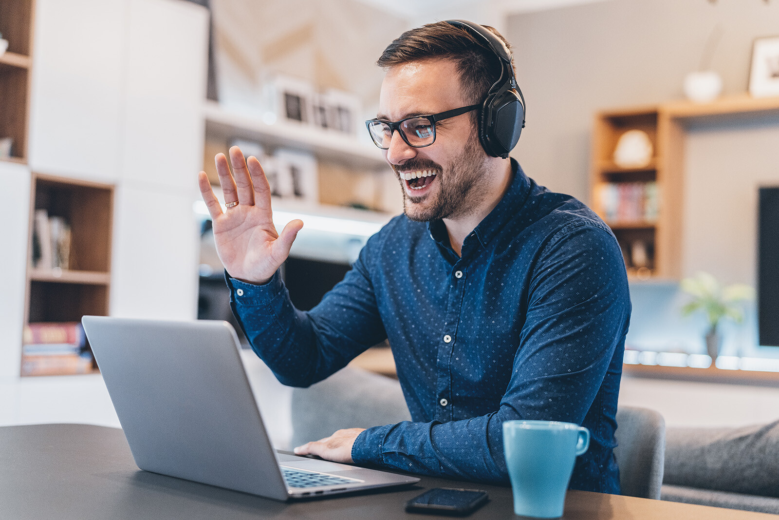 Remote worker with headphones waving at screen