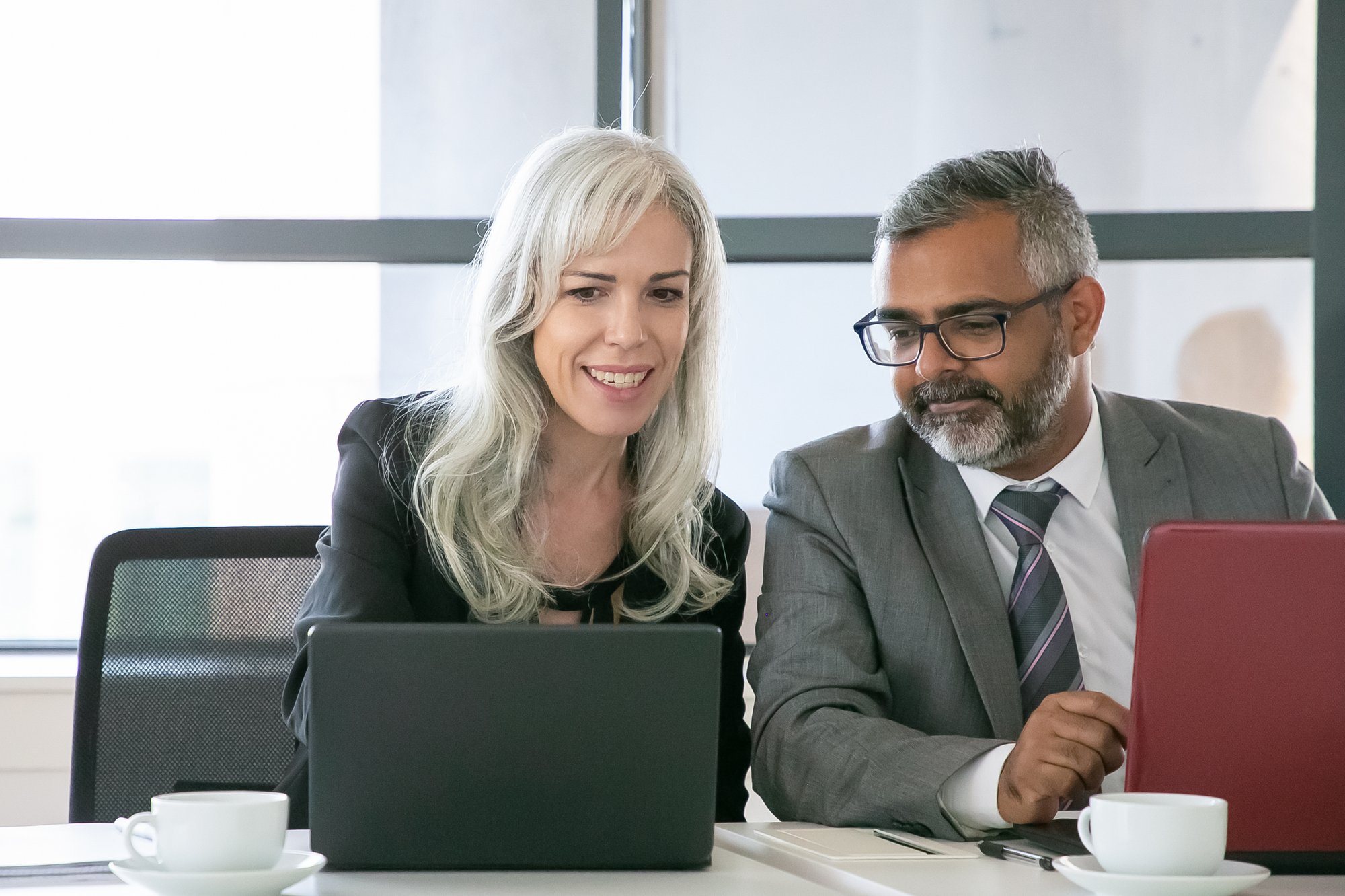 cheerful-project-manager-showing-presentation-laptop-colleague-office-medium-shot-front-view-teamwork-communication-concept